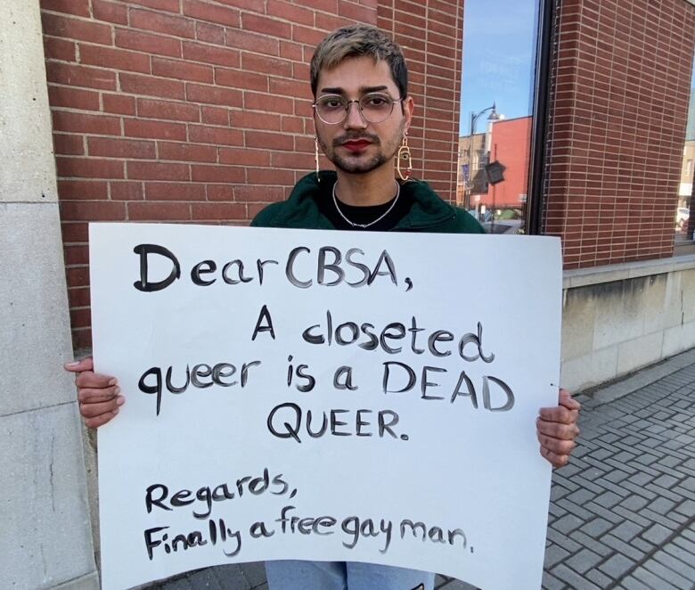 A man holds a protest sign in a downtown area.