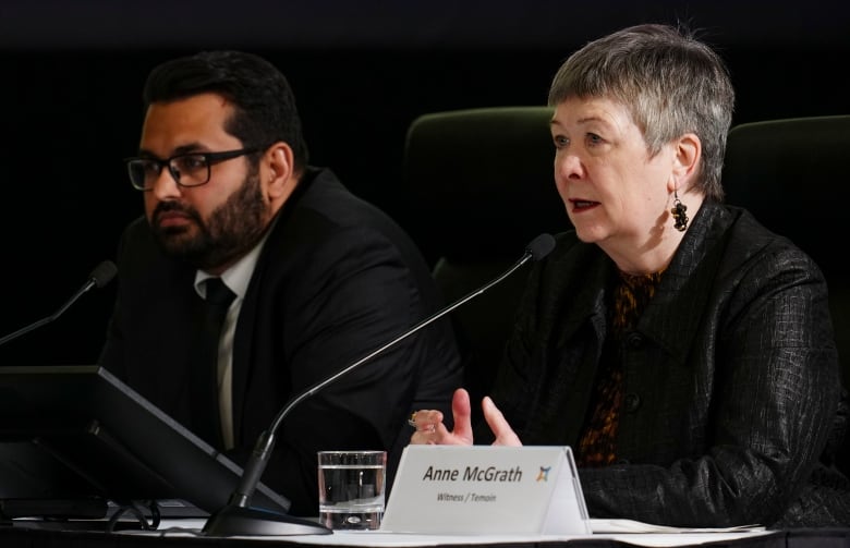 A man and a woman sit at a table and speak into microphones