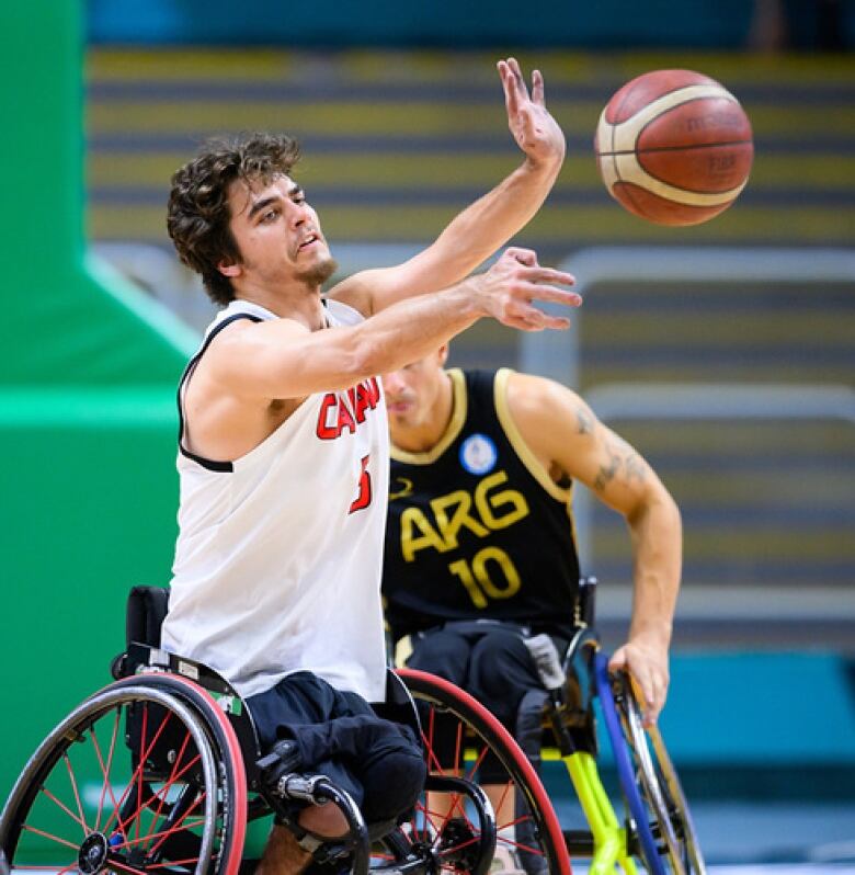 A man in a white Canada jersey competes in wheelchair basketball.