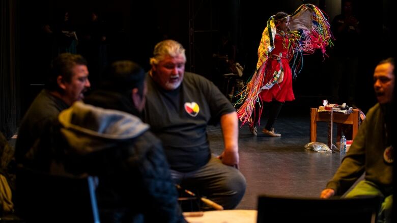 Drummers play for an Indigenous dancer.