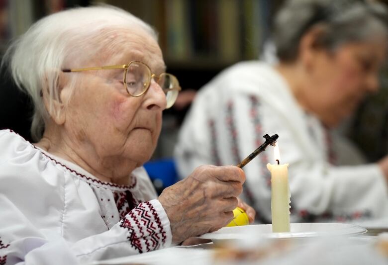 Woman decorates a Ukrainian Easter egg.