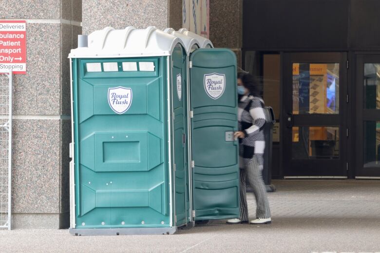 A woman is shown entering a green portable toilet.