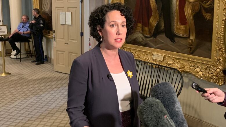 A woman stands in front of microphones.