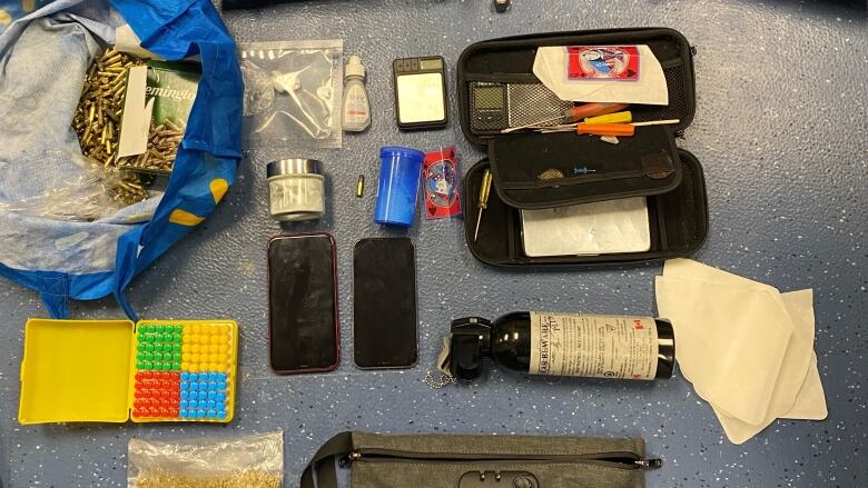 A gun, two cell phones, bags of what appear to be drugs and several other items are laid out on a table. 