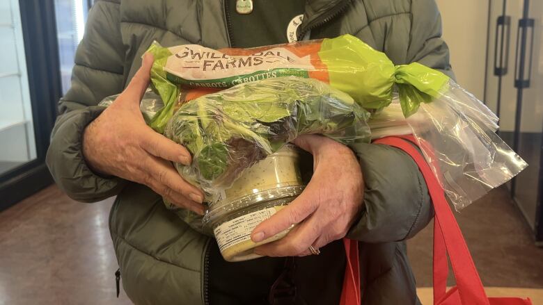 A person holds an armful of groceries.