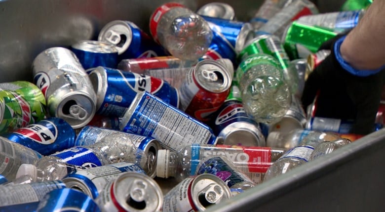 A container holding soft drink cans and plastics.