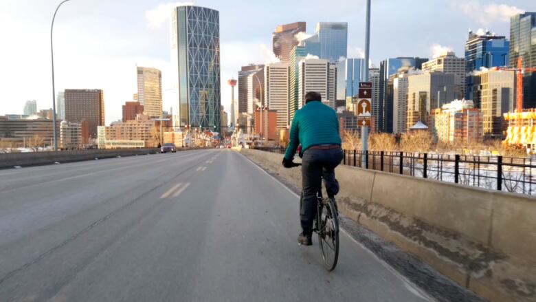 a man on a bicycle on a road. there are buildings in the background.