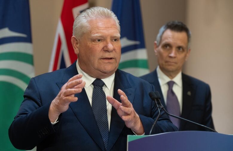 Two men in blue suits stand at a podium.