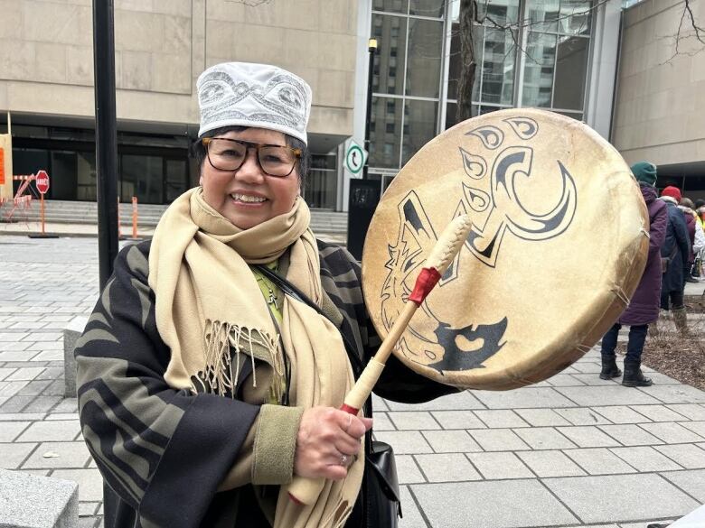 A woman bangs on a drum.