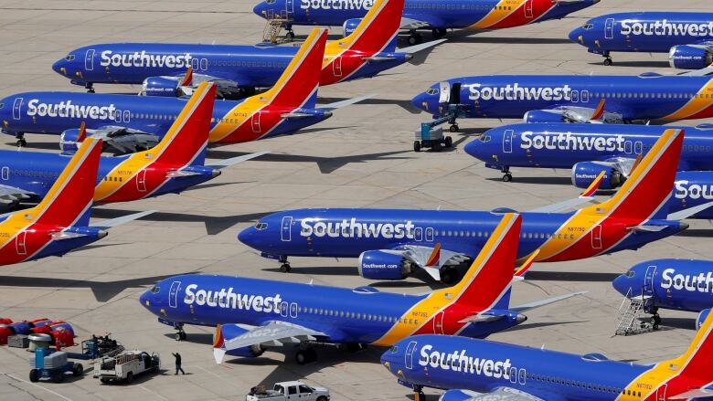 Roughly a dozen blue planes bearing the Southwest Airlines logo are grounded on a tarmac.