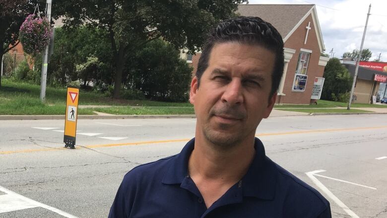 A man stands next to a street in a town.