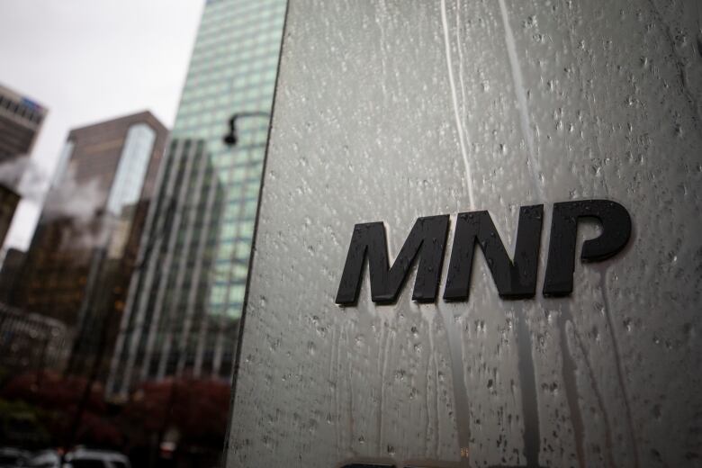 A picture of an office building with the words 'MNP' on it during a rainy day.