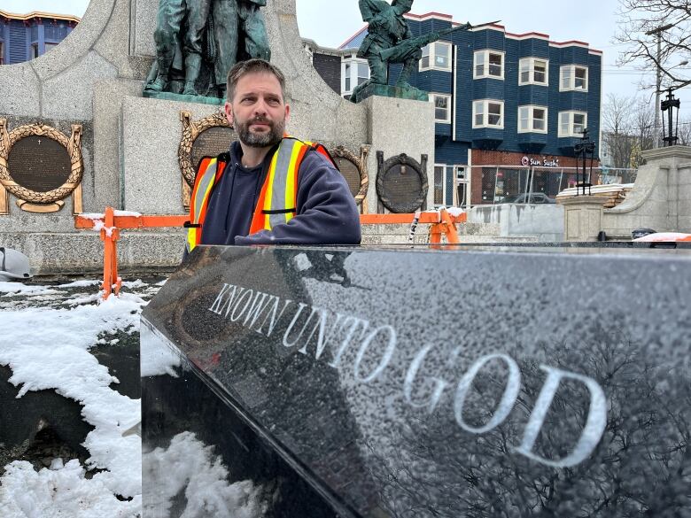 a man stands in front of a black grant tomb at the war memorial in St. John's.