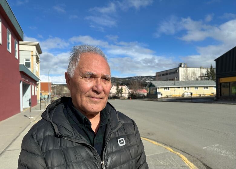 An older man with grey hair looks into the distance. 