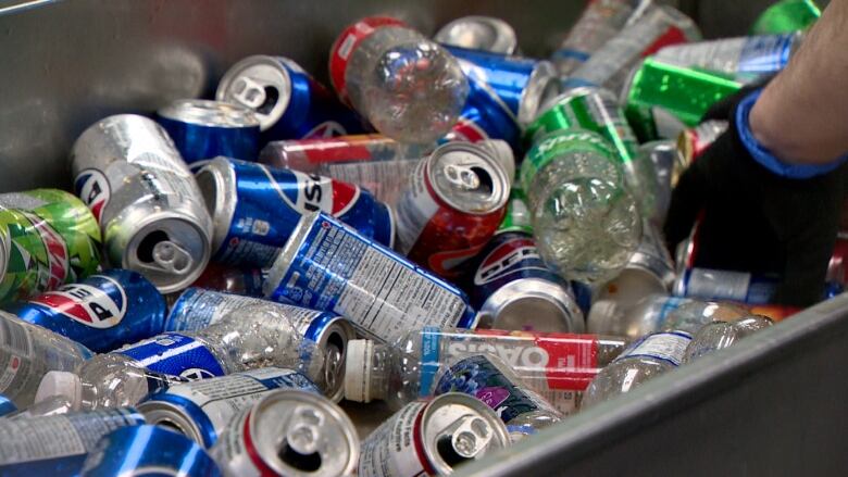 A container holding soft drink cans and plastics.