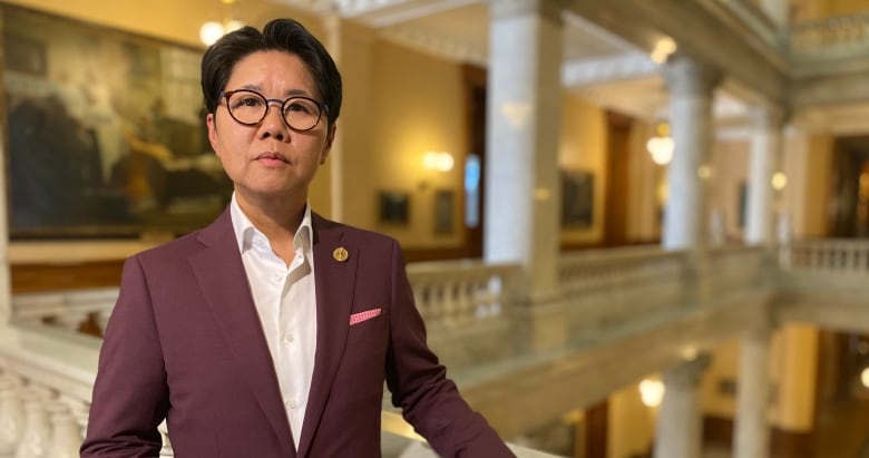 A person in a maroon suit standing in Queen's Park.