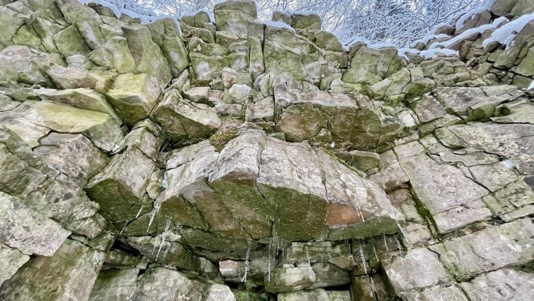 A wall of rock unevenly eroded with one chunk sticking out