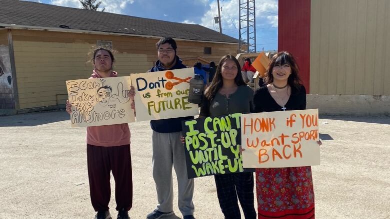 Students stand together holding signs