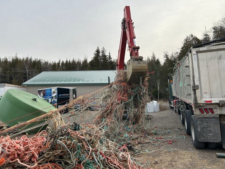 A big, tangled pile of rope being lifted by an excavator. 