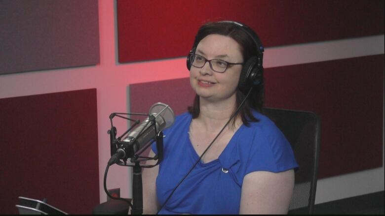 Woman with short brown hair wearing blue and glasses, smiling.