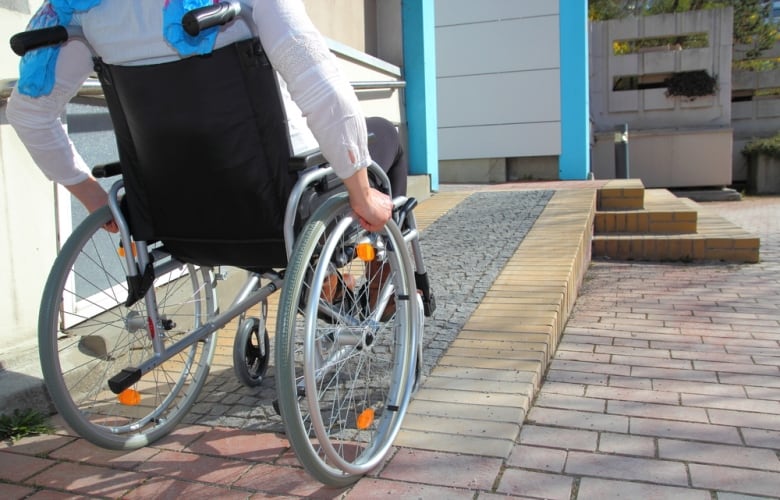 A person wheels up a wheelchair ramp.