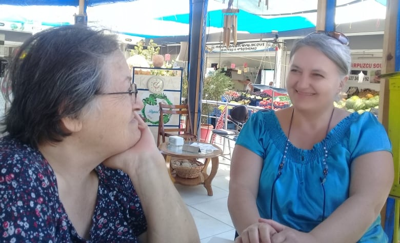 Two women sit inside a cafe. 