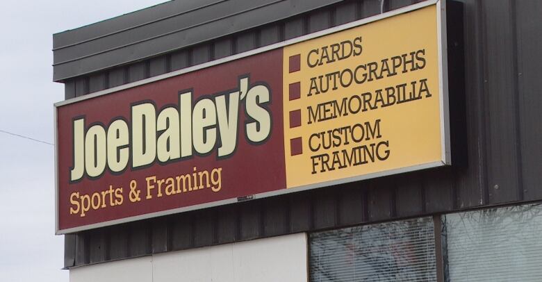 Close up of a sign on the outside of a store. The sign says Joe Daley's Sports & Framing store.