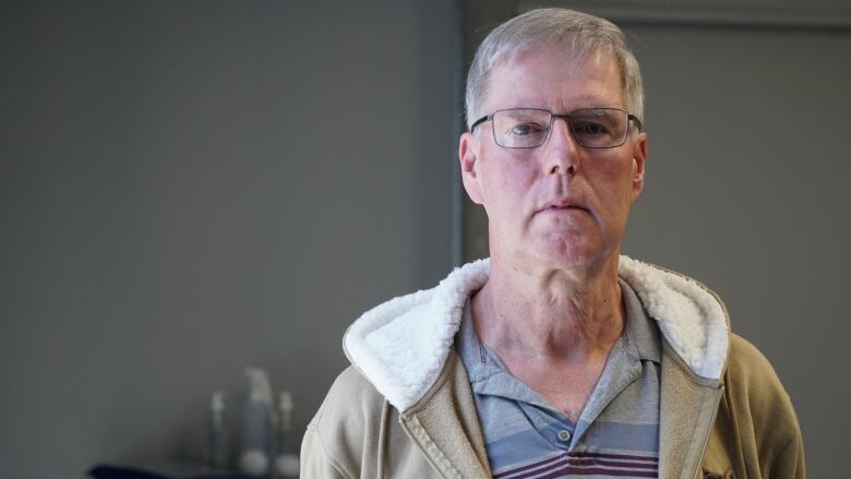 A portrait of man wearing glasses and a tan hoodie.