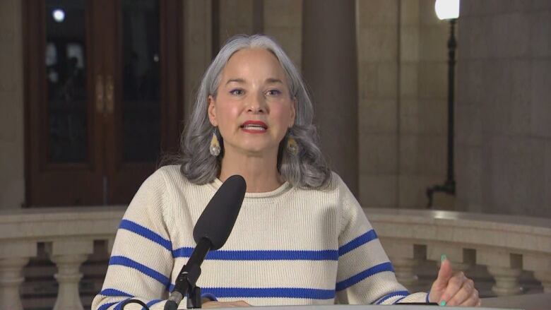 A woman stands behind a microphone.