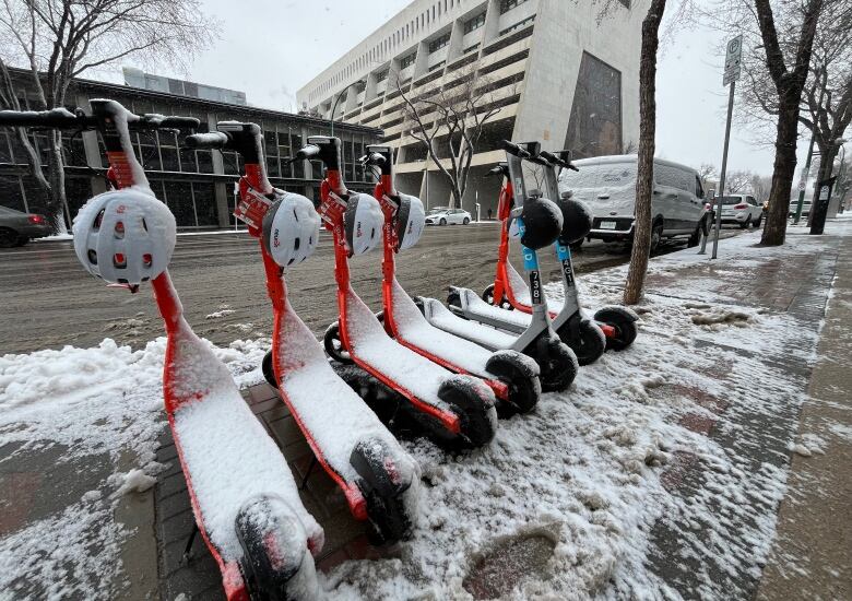 orange and silver e-scooters are covered in snow