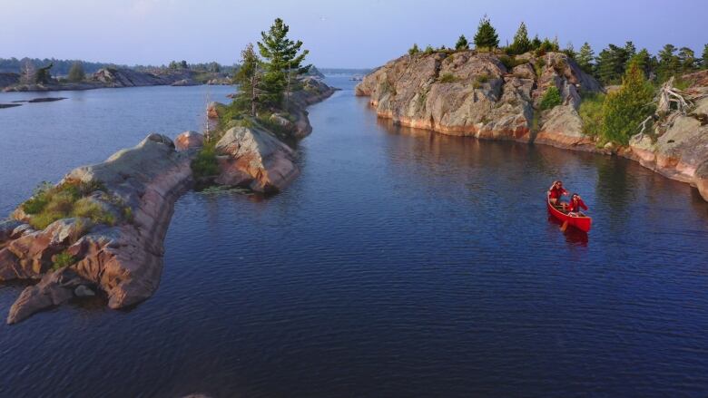 Two people in a red canoe headed down river.