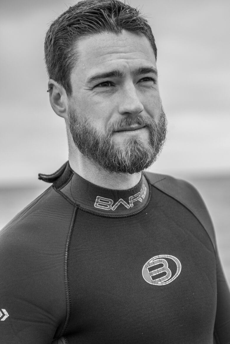 A black and white photo of a man wearing a wet suit