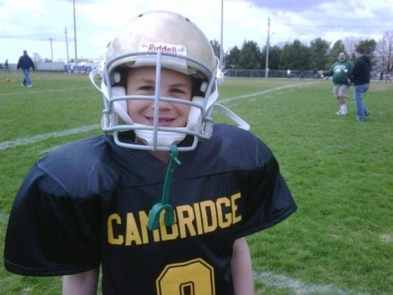 A young boy in a football helmet and jersey