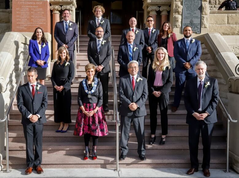 A group of people stand on outdoor stair steps and smile for a photo.