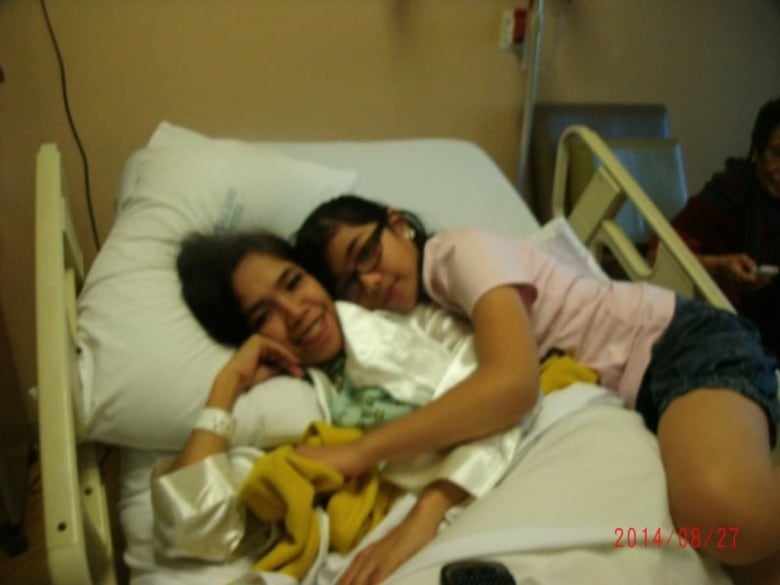 A young girl is shown with her mother, who is in a hospital bed.