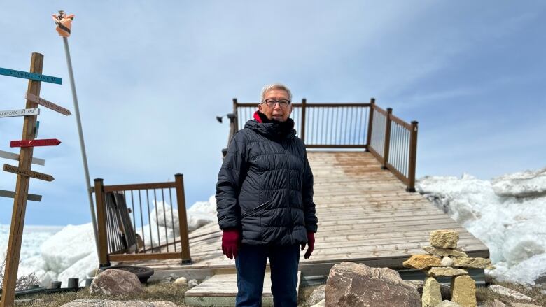 A woman standing in front of an uppended deck and massive chunks of ice.