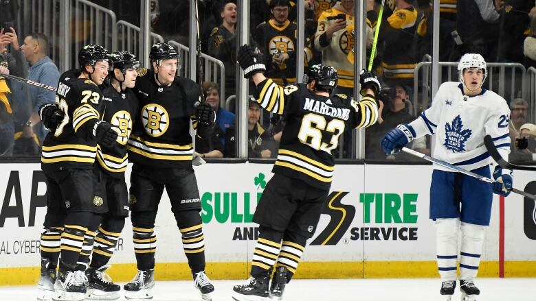 Hockey players celebrate as an opposing player skates by.