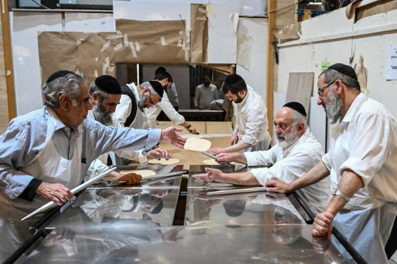 Men prepare unleavened bread at a bakery.