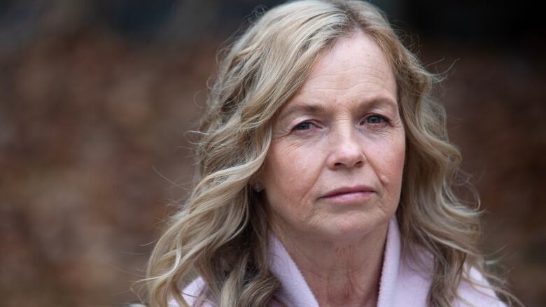 A woman looks sad and serious against a blurry background