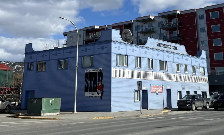 A 2-storey blue building is seen on a city street.