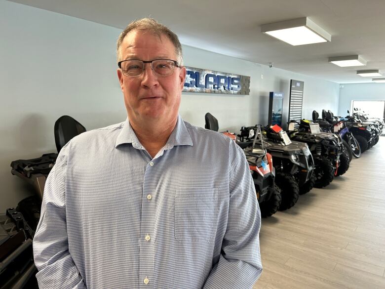 Man standing in front of all-terrain vehicles.