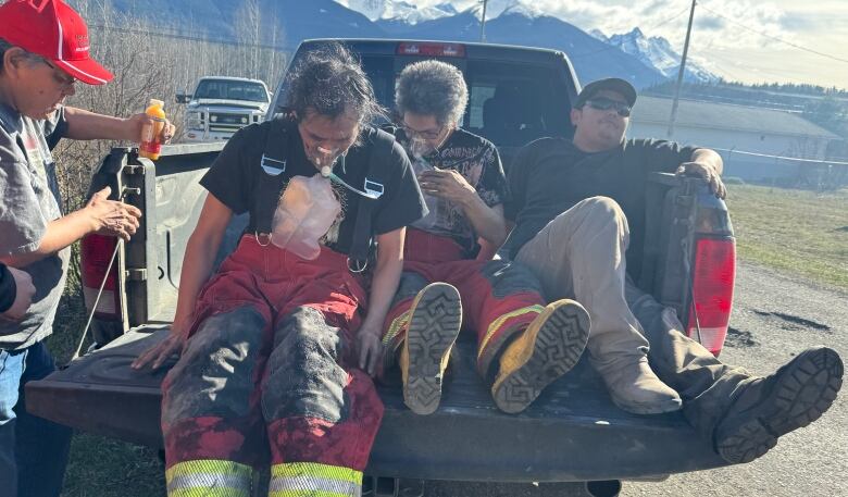 People in a truck, one using oxygen.