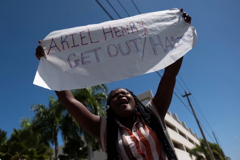 A woman holds up a white banner that reads, 