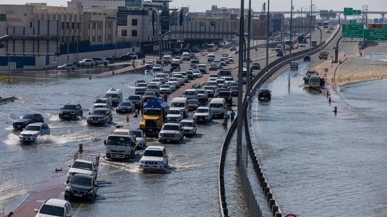 Vehicles drive through standing floodwater