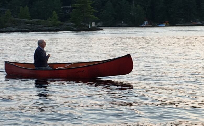 A man sitting in a red canoe on the water