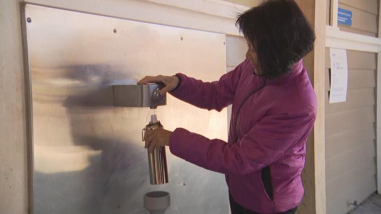 A woman uses a water fountain.