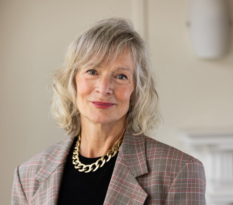 A woman wearing a plaid blazer smiles into the camera. 