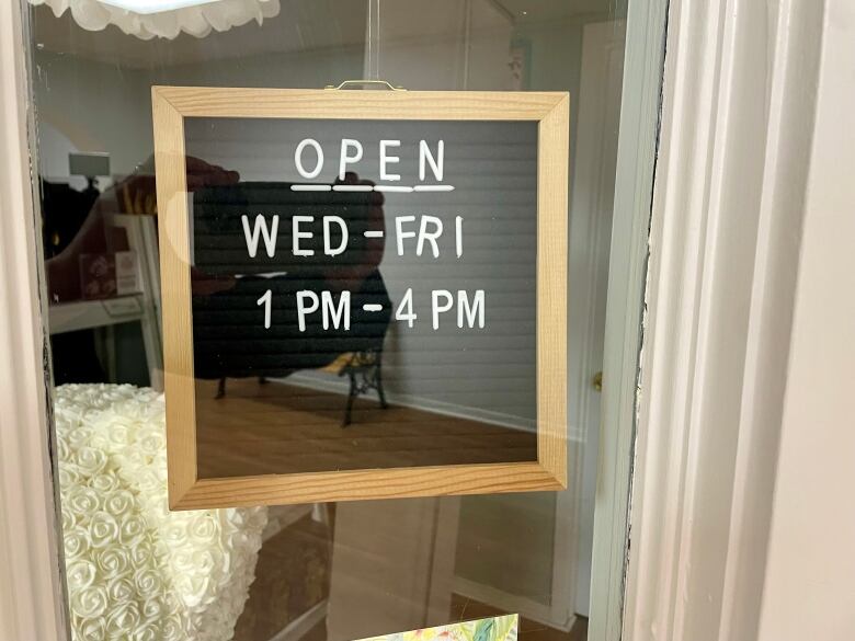 A sign in the window of a store showing that the business is open Wednesday to Fridau from 1 pm to 4 pm. 