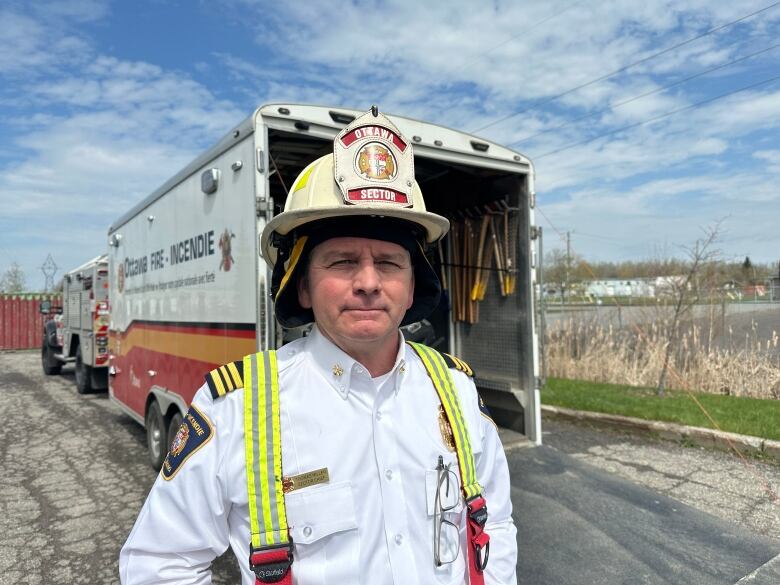 A fire chief stands in front of a truck