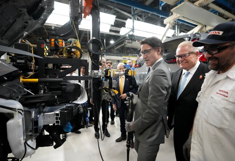 Prime Minister Justin Trudeau, left, and Ontario Premier Doug Ford, centre, work along the vehicle assembly line before at an event announcing plans for a Honda electric vehicle battery plant in Alliston, Ont., on Thursday, April 25, 2024.